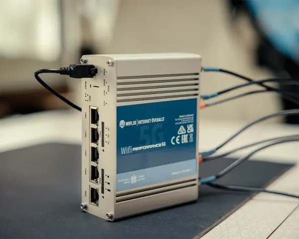 En silverfärgad 5G-router med flera LAN-portar och antennkablar. Perfekt för mobilt bredband i Europa.