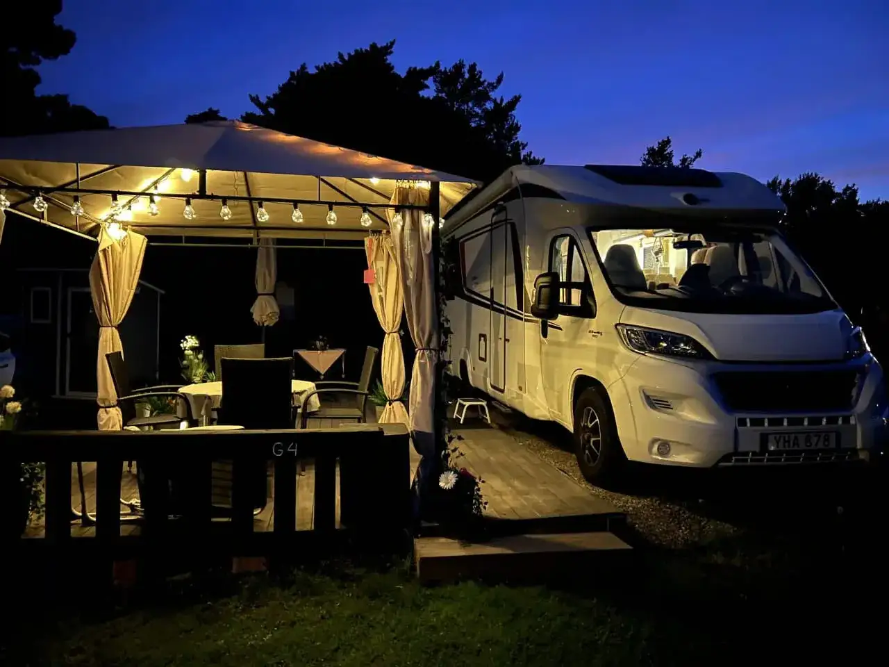 Kvällsstämning på Marholmen camping med husbil parkerad vid ett upplyst lusthus.