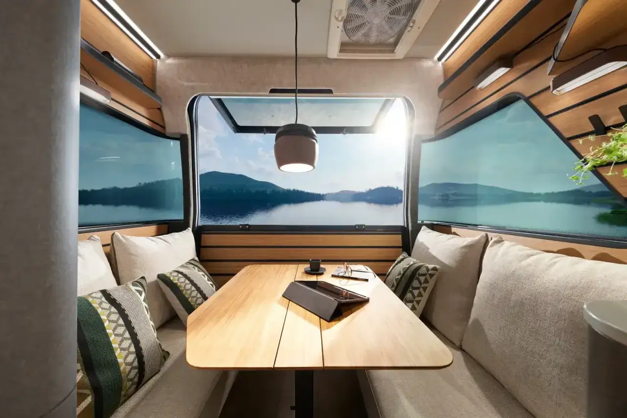 Mysig sittgrupp i en Hymer Venture S med fantastisk utsikt &ouml;ver en sj&ouml; och berg. Perfekt f&ouml;r avkoppling.