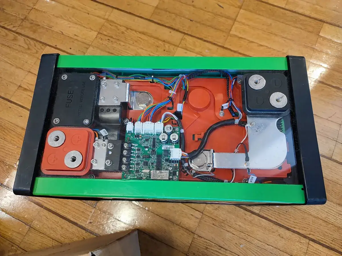 &Ouml;ppen l&aring;da med gr&ouml;nt chassi visar ett komplext bms batteri med kretskort, kablar och anslutningar.