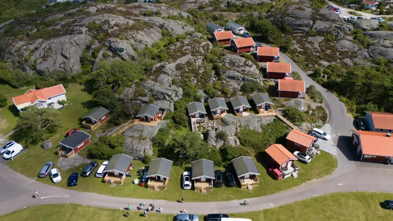 En idyllisk camping p&aring; Orust med r&ouml;da stugor och klippor.