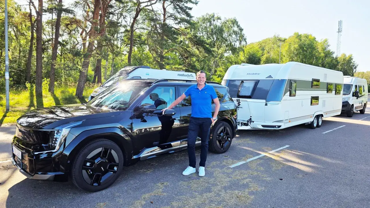 Man vid en svart elbil som drar en husvagn och en campervan. Perfekt f&ouml;r sommarens &auml;ventyr!