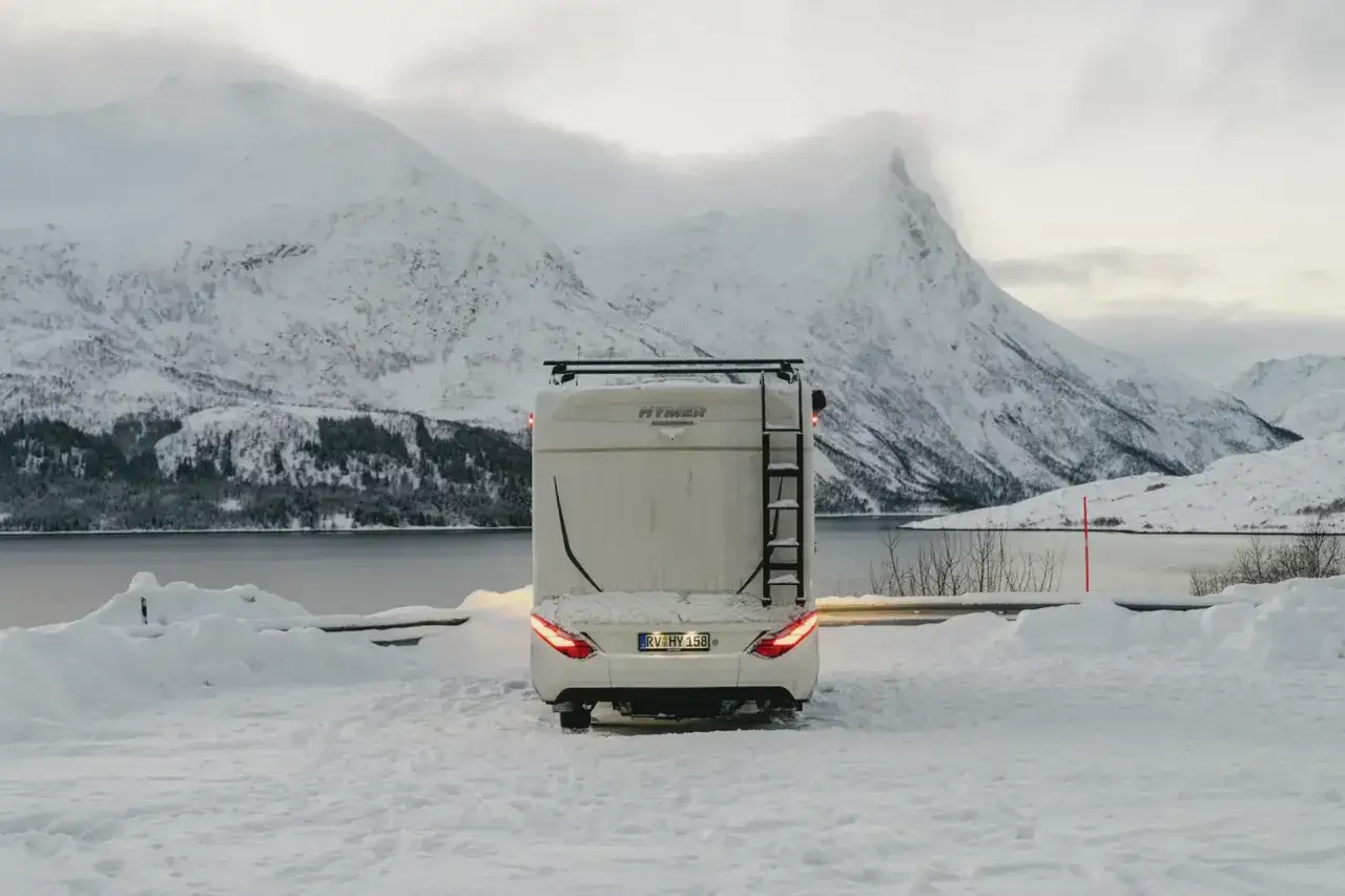 Husbil parkerad i sn&ouml;ig norsk fj&auml;llmilj&ouml;, redo f&ouml;r att uppleva norrsken i Norge.