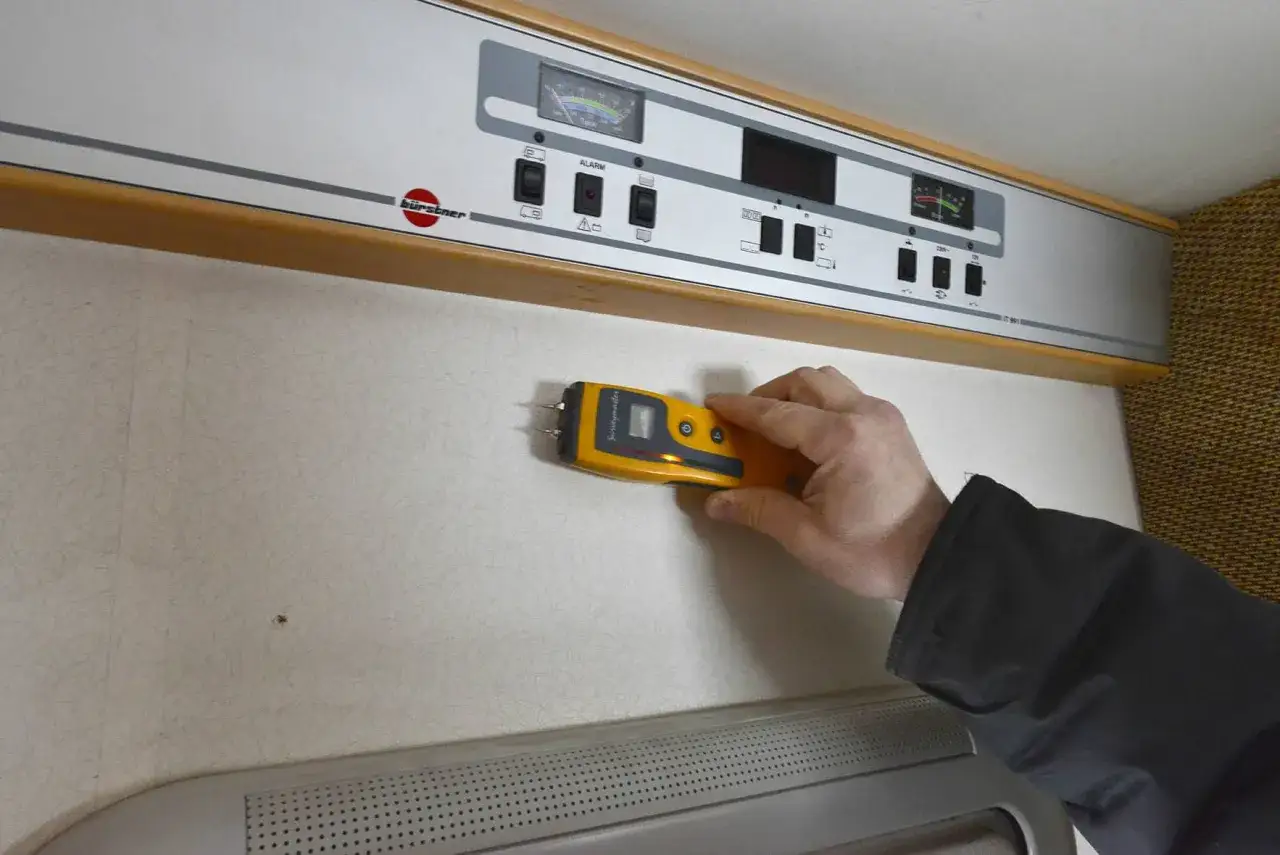 Hand h&aring;ller fuktm&auml;tare mot v&auml;gg f&ouml;r fukttest protokoll.